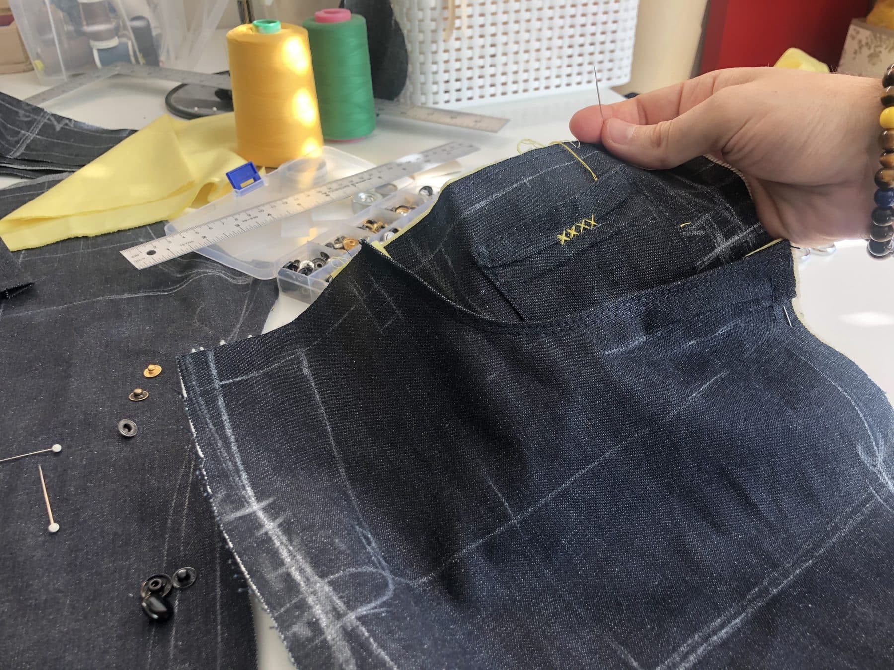 Hands pinning chalk-marked denim with yellow thread on the Alter Up workbench